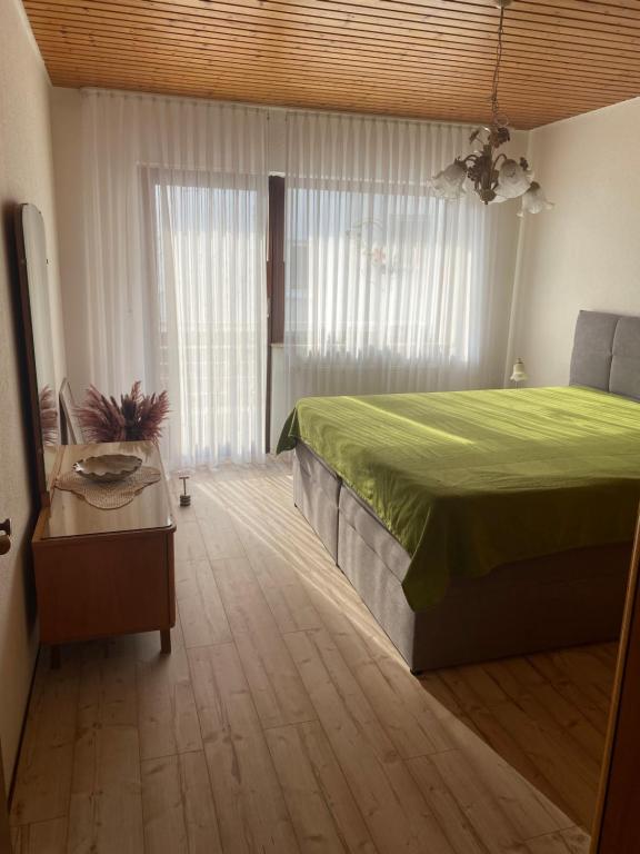 a bedroom with a green bed and a table at Ferienwohnung Elli in Nieder-Olm