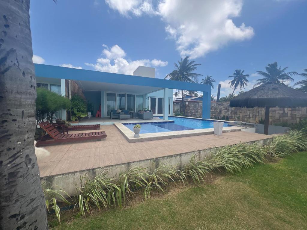 a house with a swimming pool and an umbrella at Ocean front privacy and comfort! in Pitangui