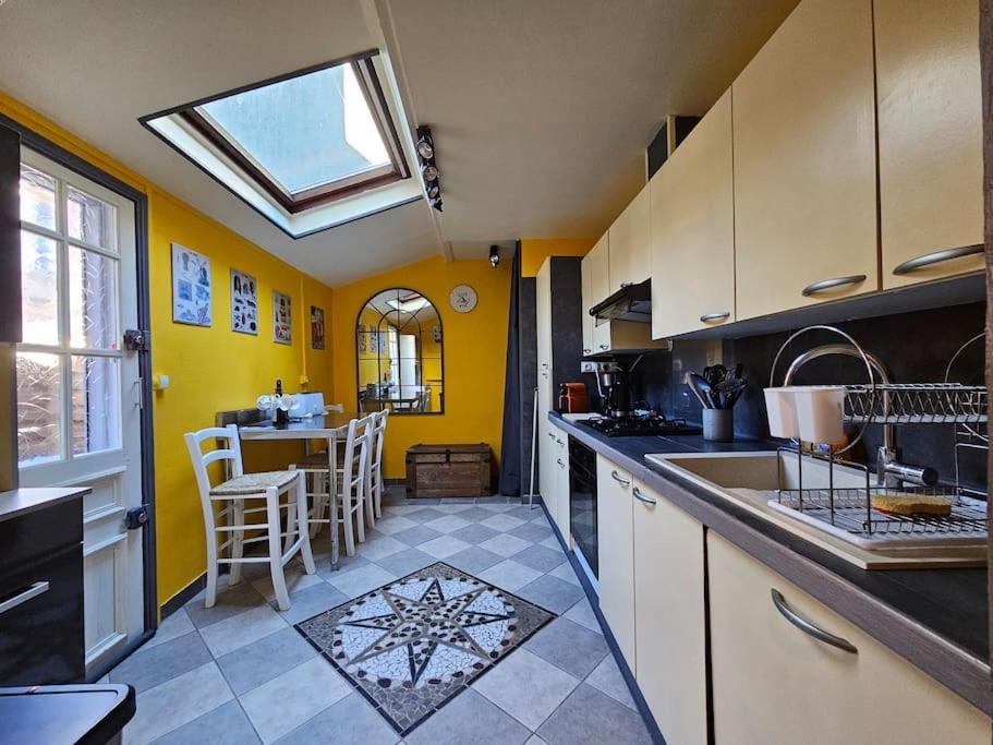 une cuisine avec des murs jaunes et une lucarne dans l'établissement Les Caloges , maison avec terrasse, à Étretat