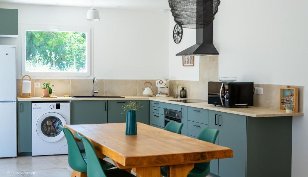 a kitchen with a wooden table and green chairs at La Farigoule - Villa avec spa, clim, terrasse in La Roque-sur-Cèze