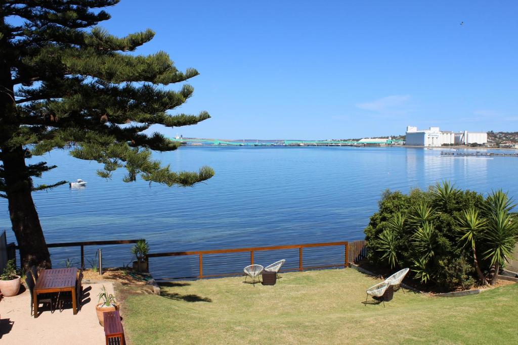 a view of a lake with chairs and a tree at Bay 10 - Suites and Apartments in Port Lincoln