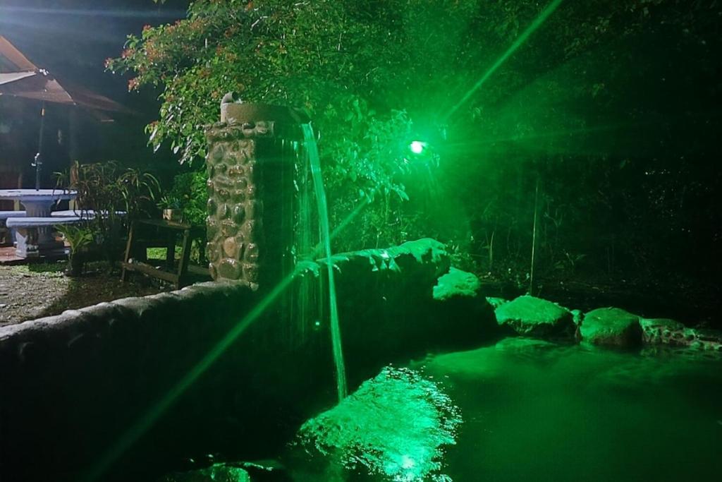 a water fountain with green lights at night at Habitación rodeada de las copas de los árboles in San Ramón