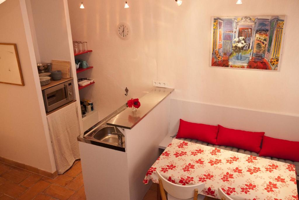 アルルにあるStudio Apartment Centre Historiqueの小さなキッチン(シンク、赤い枕付きのテーブル付)