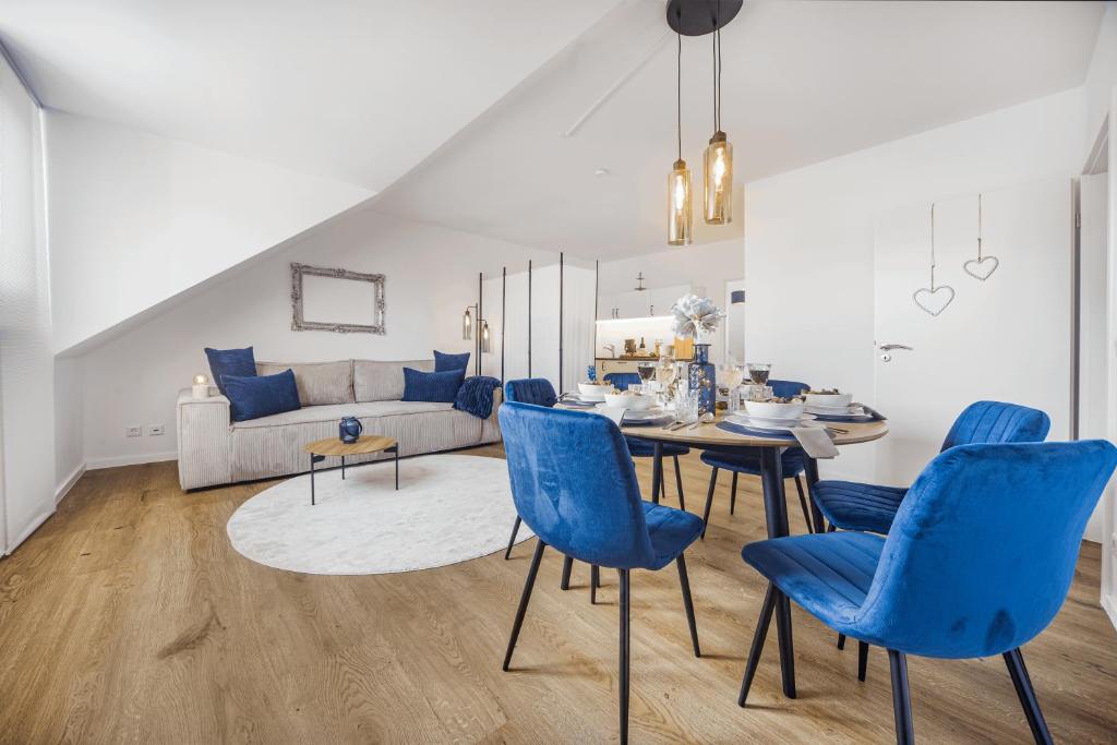 ein Wohnzimmer mit einem Tisch und blauen Stühlen in der Unterkunft Exquisite Superior Suite 80m2 mit 2 Schlafzimmern & Badewanne - Messe Essen in Essen