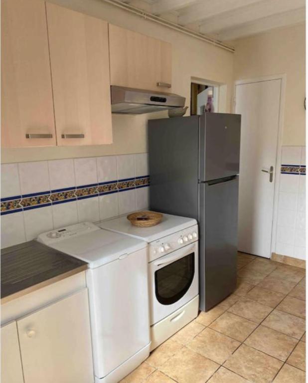 La cuisine est équipée d'une cuisinière blanche et d'un réfrigérateur. dans l'établissement Maison Vierville, à Vierville-sur-Mer