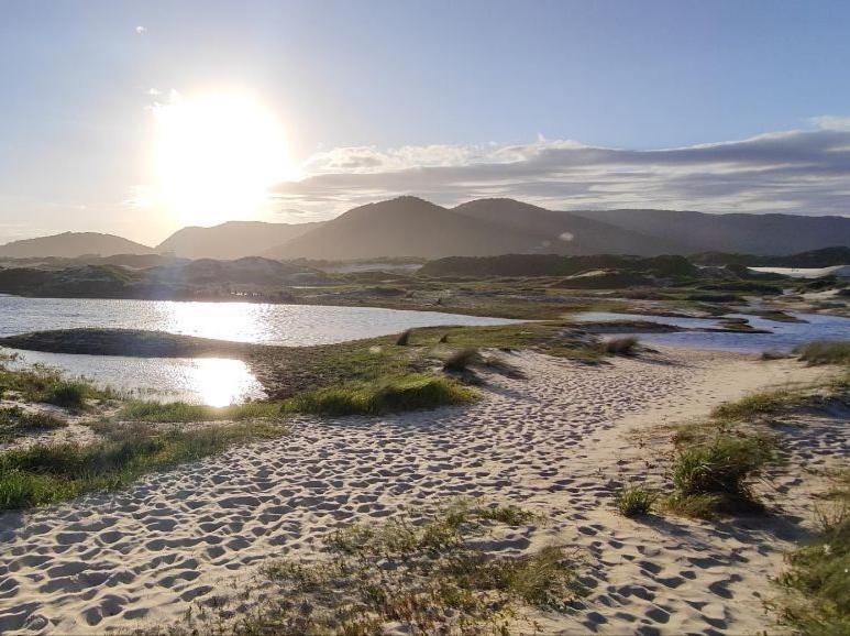 a beach with the sun shining on the water at Studio Dunas Porto Lagoa in Florianópolis