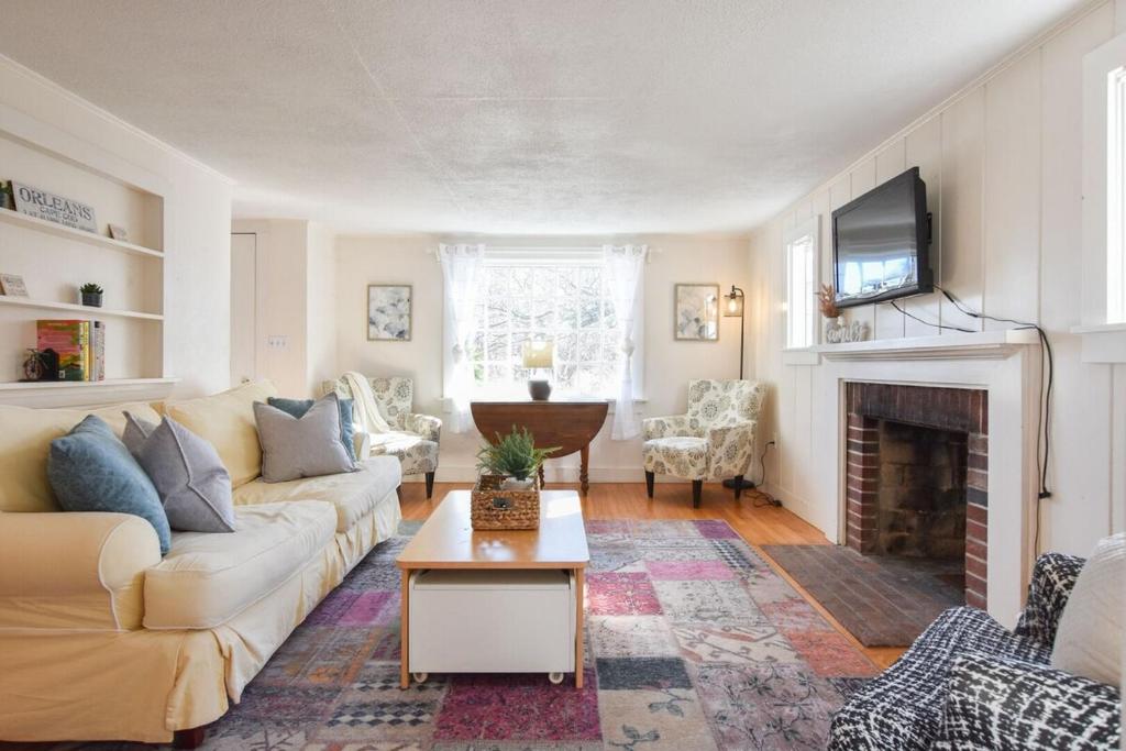 a living room with a couch and a fireplace at 15556 - Walk to Skaket Beach or Bike to Rail Trail w Outdoor Shower SUP Board Ping Pong Table in Orleans