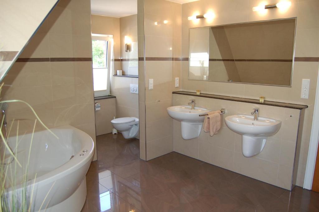 a bathroom with two sinks and a tub and a toilet at Strandhaus Deichvoigt in Cuxhaven