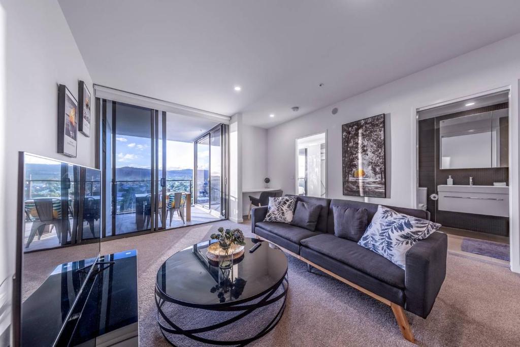 a living room with a couch and a glass table at Modern APT in Toowong with Mountain View in Brisbane
