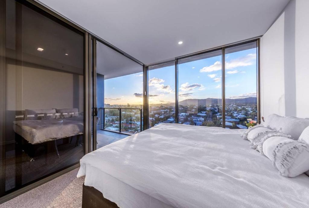 a bedroom with a large white bed and glass windows at Modern APT in Toowong with Mountain View in Brisbane