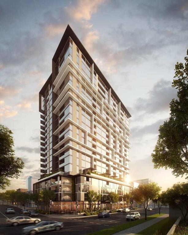 a large white building with cars parked in a parking lot at Modern APT in Toowong with Mountain View in Brisbane