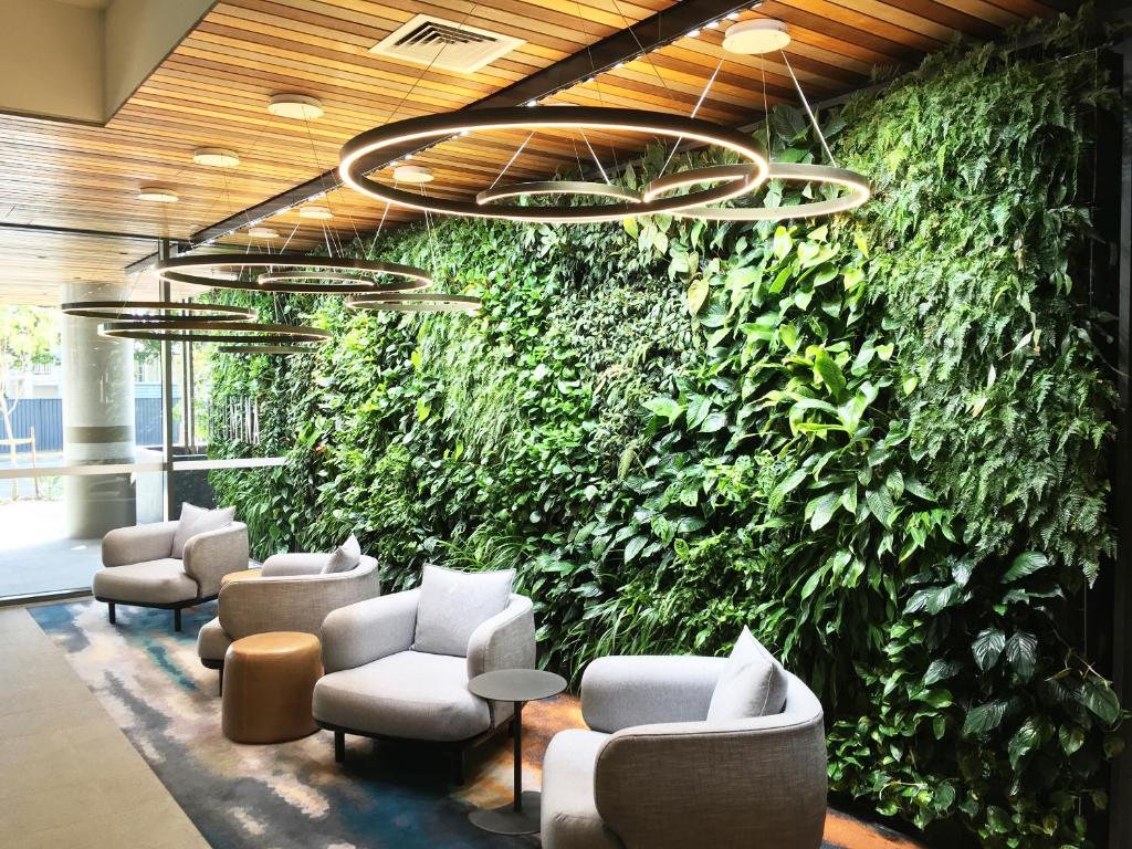 a green wall in a waiting room with chairs and tables at Modern APT in Toowong with Mountain View in Brisbane