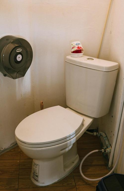 a white toilet in a bathroom with a toilet paper dispenser at WaterMellow Hostel in Koh Tao