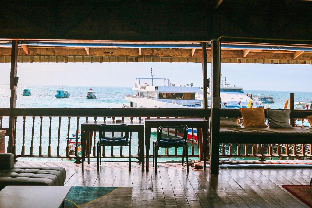 a table and chairs and a boat in the water at WaterMellow Hostel in Koh Tao