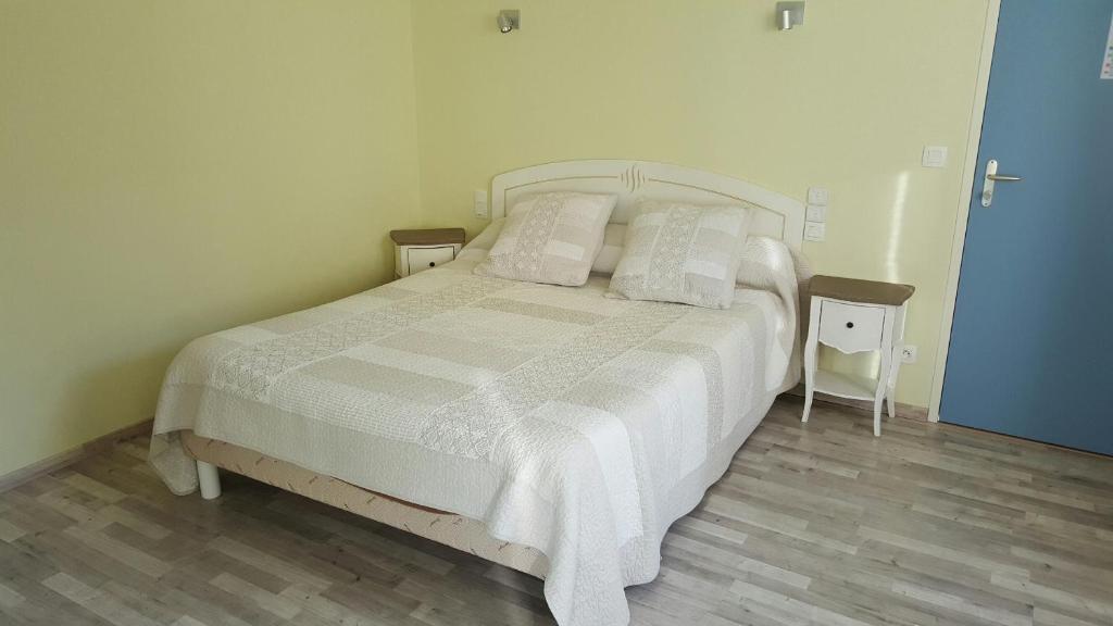 1 dormitorio con 1 cama con sábanas y almohadas blancas en Hotel de la Gare en Mézidon-Canon