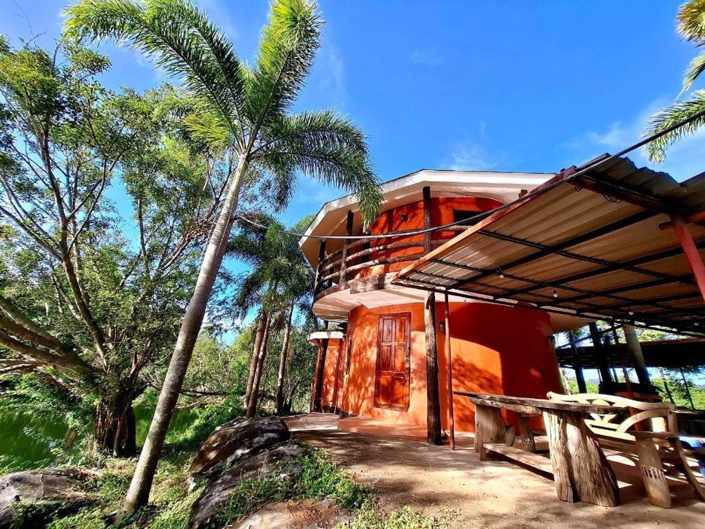 a house with palm trees in front of it at บ้านดิน 2 ชั้น in Khanong Phra