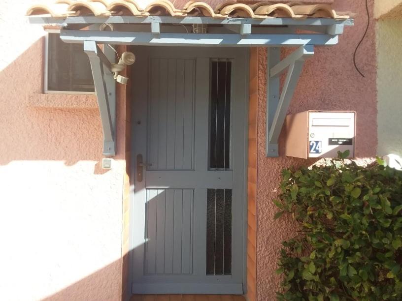 une porte menant à une maison avec auvent et aolice dans l'établissement les pieds dans l eau, à Le Castellas