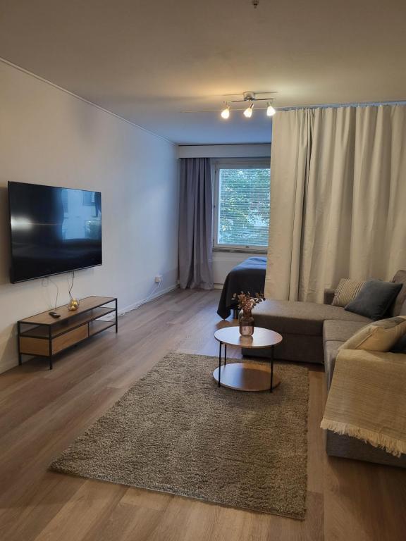 a living room with a couch and a tv at Kaunis kaupunkiasunto, täydellinen sijainti! in Lahti