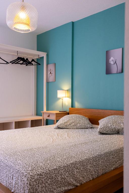 une chambre avec un lit avec un mur bleu dans l'établissement Joli appartement proche de la mer, au Pradet