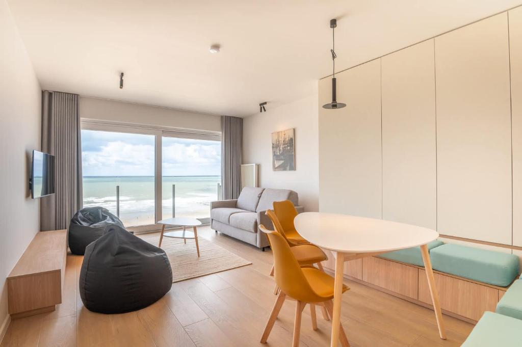 a living room with a table and a couch at Luxurious studio with a stunning view in Middelkerke