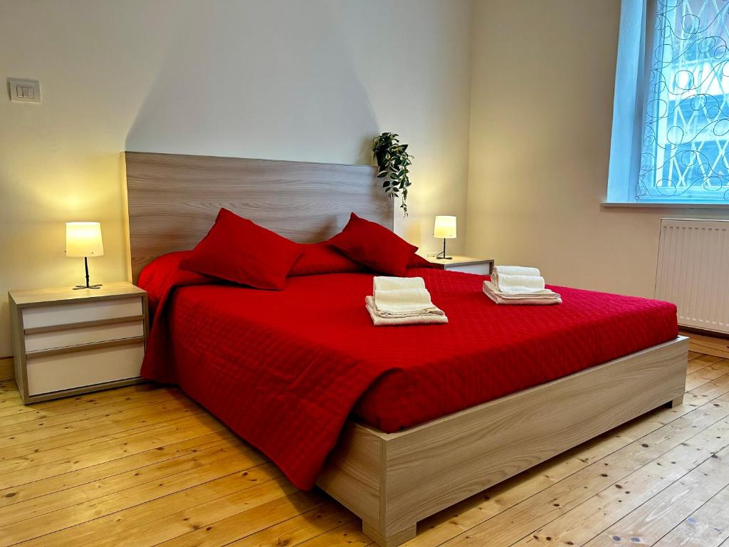 ウーディネにあるLuxury Allo Apartment in center of Udineのベッドルーム1室(赤いベッド1台、タオル2枚付)