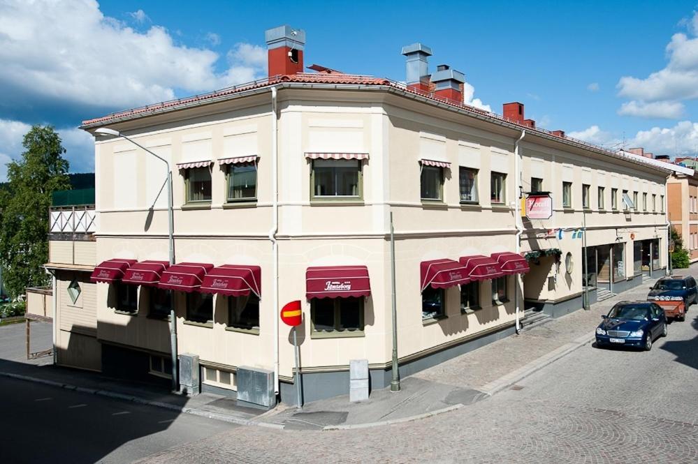 un gran edificio blanco con toldos rojos en una calle en Hotel Jämteborg en Östersund