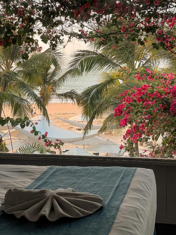 a bedroom with a view of a beach and palm trees at Nordestina Loft in Icaraí