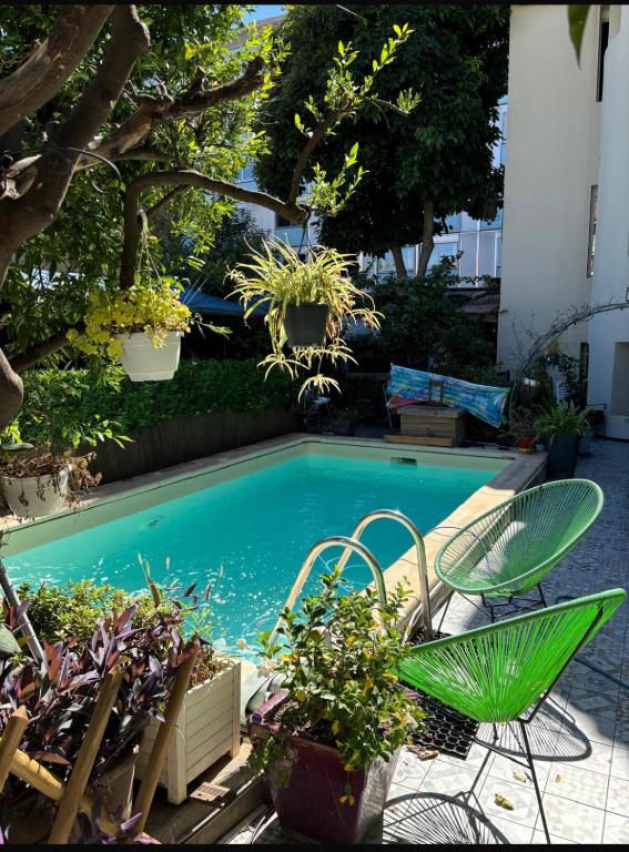 une piscine avec une chaise verte et quelques plantes dans l'établissement Villa CALIFORNIA, à Nice