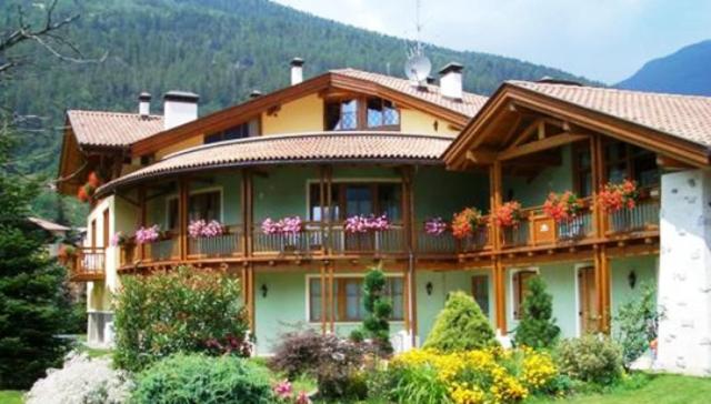 a large house with a balcony with flowers on it at Residence Il Giardino in Croviana