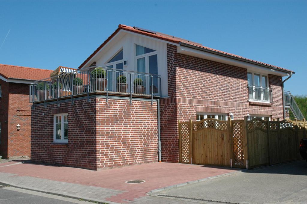 ein Backsteinhaus mit einem Balkon und einem Zaun in der Unterkunft Boardinghouse in Büsum