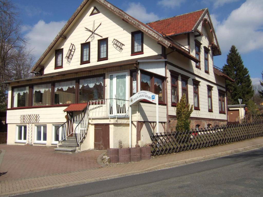 uma grande casa branca com um alpendre numa rua em Haus am Kurpark em Sankt Andreasberg