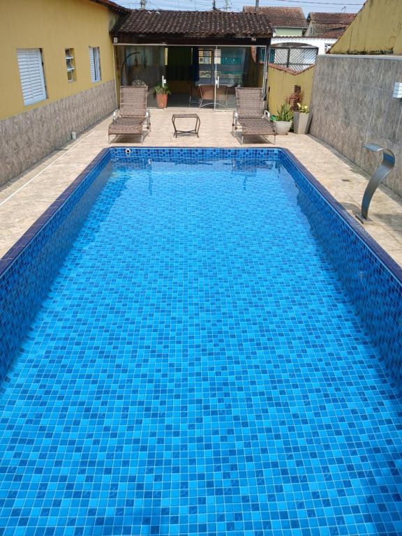 a large swimming pool with blue tiles in a yard at 600 metros da praia piscina e churras 3 vagas in Mongaguá