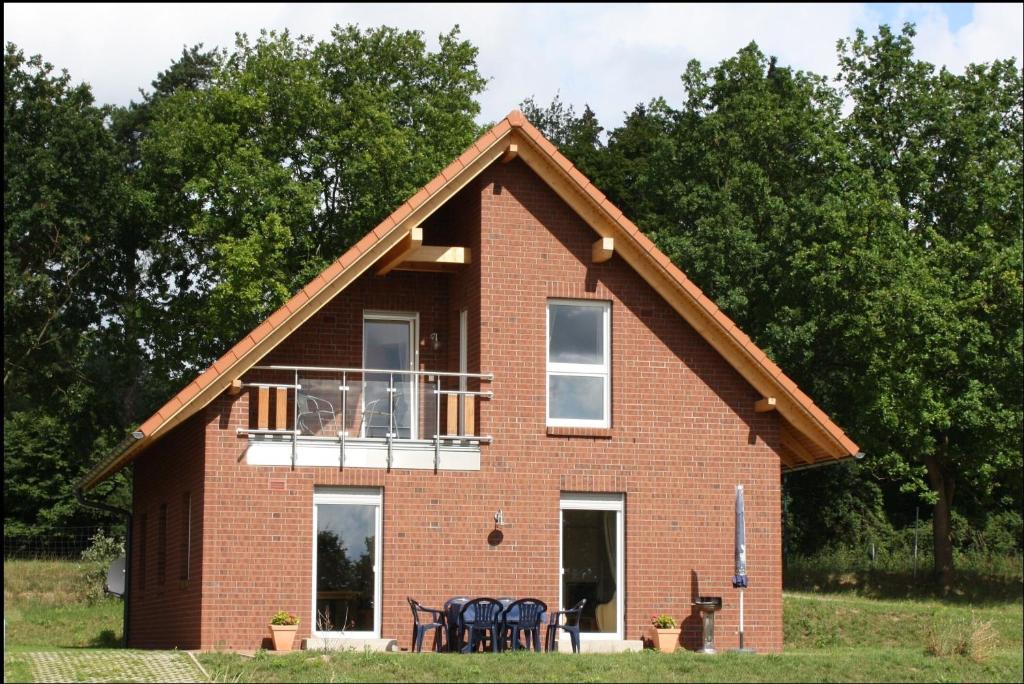 a red brick house with a balcony and tables at Großzügiges Ferienhaus am Krakower See inkl Boot und Badesteg in Krakow am See