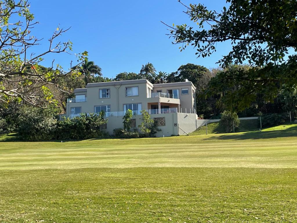 a large white house on a grassy field at 6th Tee Southbroom in Southbroom