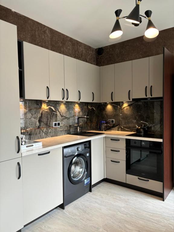a kitchen with white cabinets and a washer and dryer at Business Park Sofia Cozy Lux & Private Garage Option in Sofia