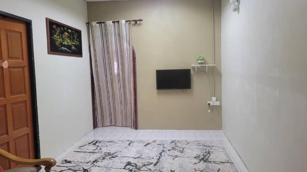 Habitación con ducha y TV en la pared. en Ummi Homestay, en Kampong Batu Tiga