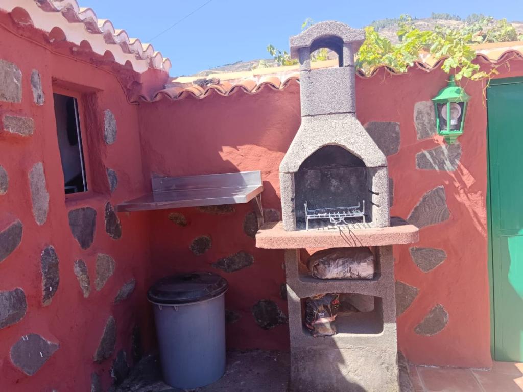 een buitenoven in een rood gebouw met een vuilnisbak bij Casa García Pérez in Las Lagunetas
