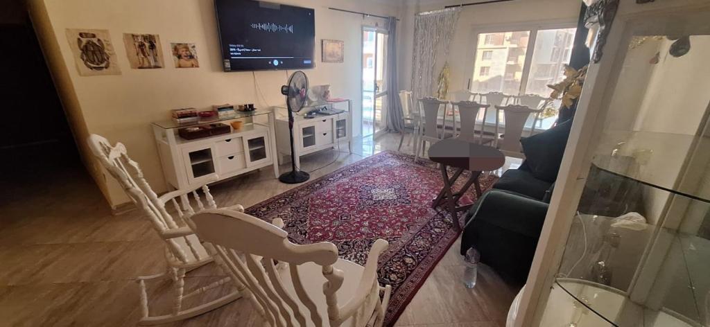 Una sala de estar con sillas, una mesa y un televisor. en one cozy bedroom, en New cairo