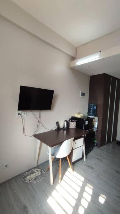 a room with a table and a television on a wall at natural minimalist apt ice bsd in Cilandak