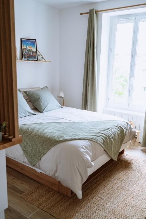 une chambre avec un lit avec des draps blancs et une fenêtre dans l'établissement Superbe studio rénové proche Métro avec garage, à Oullins