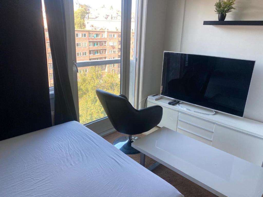 Un dormitorio con una cama, un televisor y una silla. en Oslo resident 33L, en Oslo