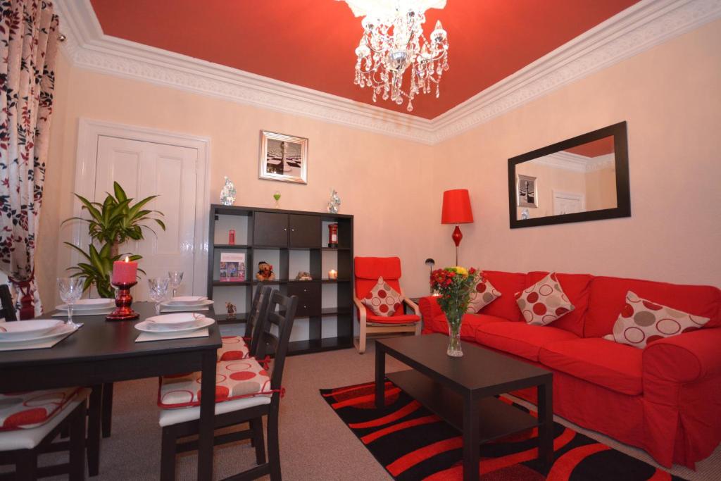a living room with a red couch and a table at Wallace Apartment in Stirling