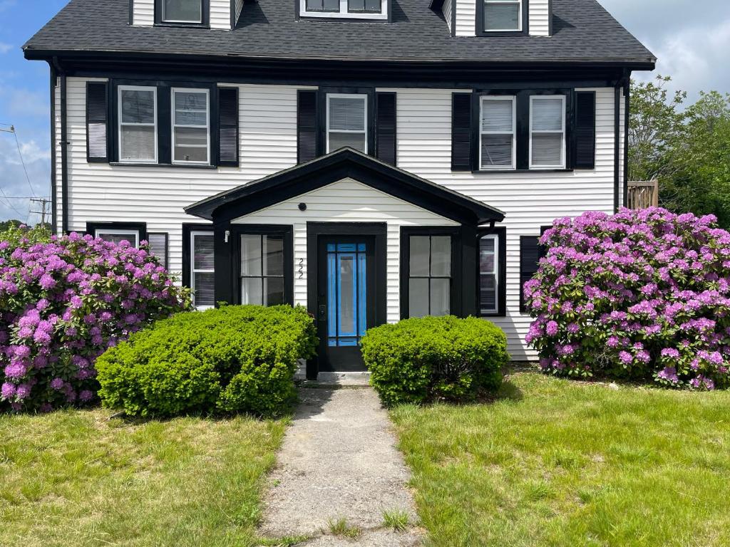a black house with a blue door and purple flowers at Charming Condo near Gillette Stadium in Sharon