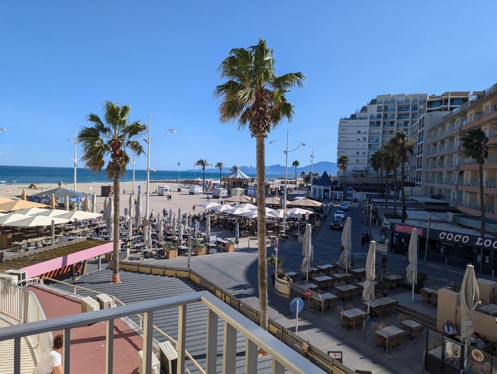 - une vue sur une plage bordée de palmiers et de chaises dans l'établissement Ti Caraïbe appartement vue mer et parking gratuit du 1 juin au 30 septembre, à Canet