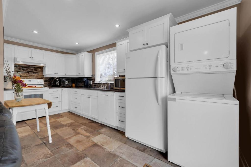 Una cocina con gabinetes blancos y un refrigerador blanco. en Cottage Feel in the City Close to Everything, en Saint John