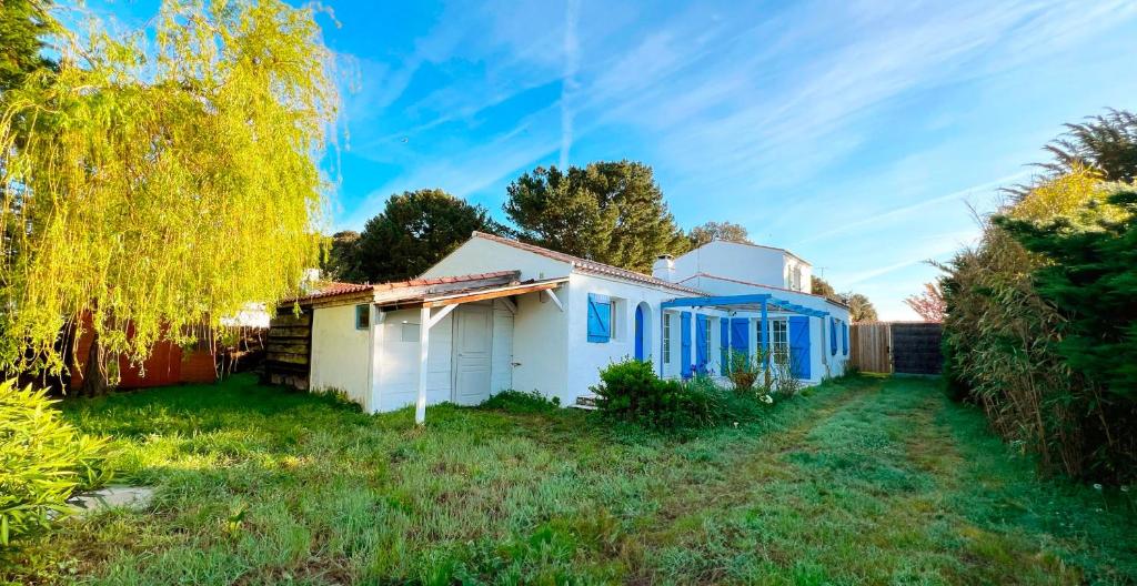 une maison blanche avec des fenêtres bleues et une cour dans l'établissement Maison calme entre plage et centre, à Noirmoutier-en-l'lle