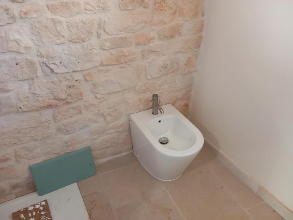 a bathroom with a white bidet and a stone wall at Trullo Amedee in Ostuni