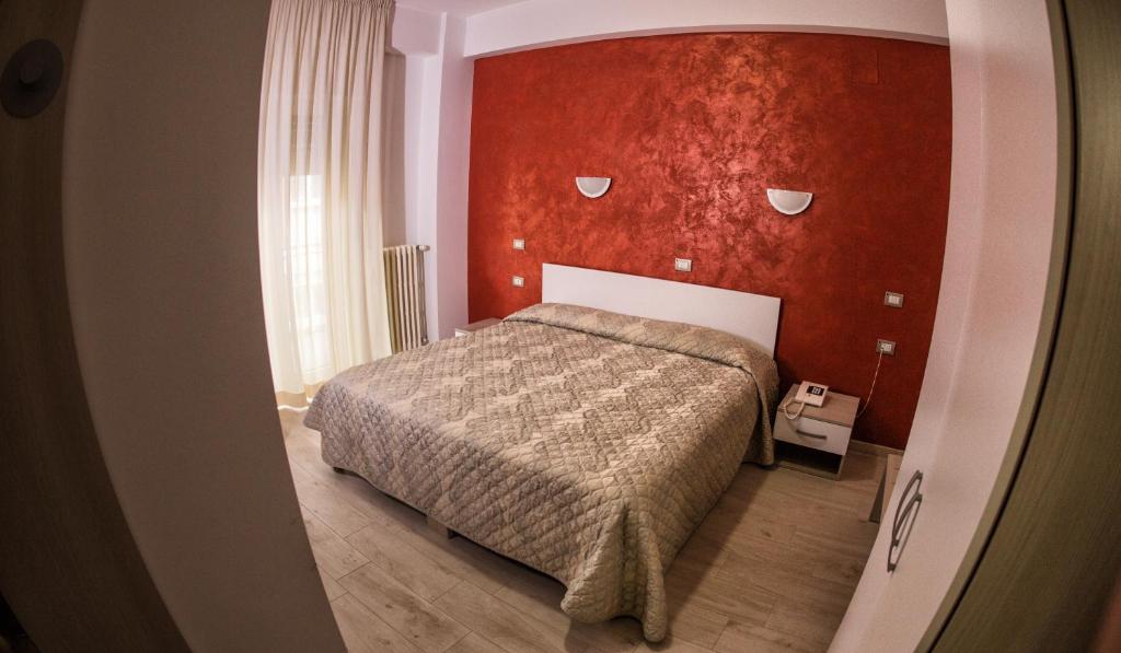 Tourist Hotel في بوتنزا: غرفة نوم بسرير وجدار احمر
