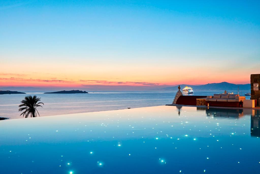 a pool with a view of the ocean at sunset at Bill & Coo Mykonos -The Leading Hotels of the World in Mýkonos City