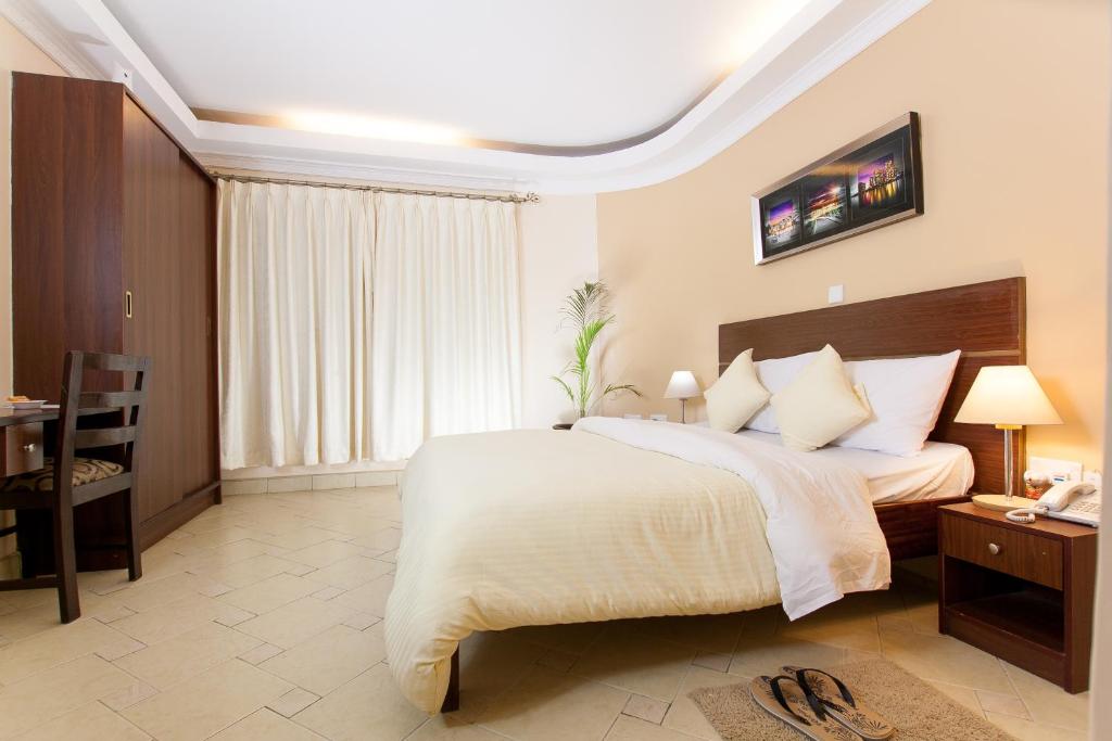 a bedroom with a large bed and a table and a desk at Capital Heights Hotel in Nairobi